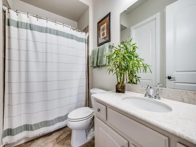 a bathroom with a granite countertop sink a toilet and shower