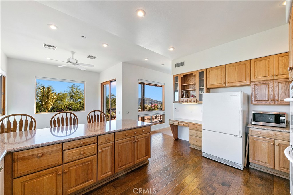 8400 Mipolomol Road Malibu, CA 90265 - Photo 21 of 58 a kitchen with stainless steel appliances granite countertop a refrigerator a stove a sink dishwasher and white cabinets with wooden floor