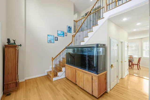 a living room with couches chandelier and a dining table with wooden floor