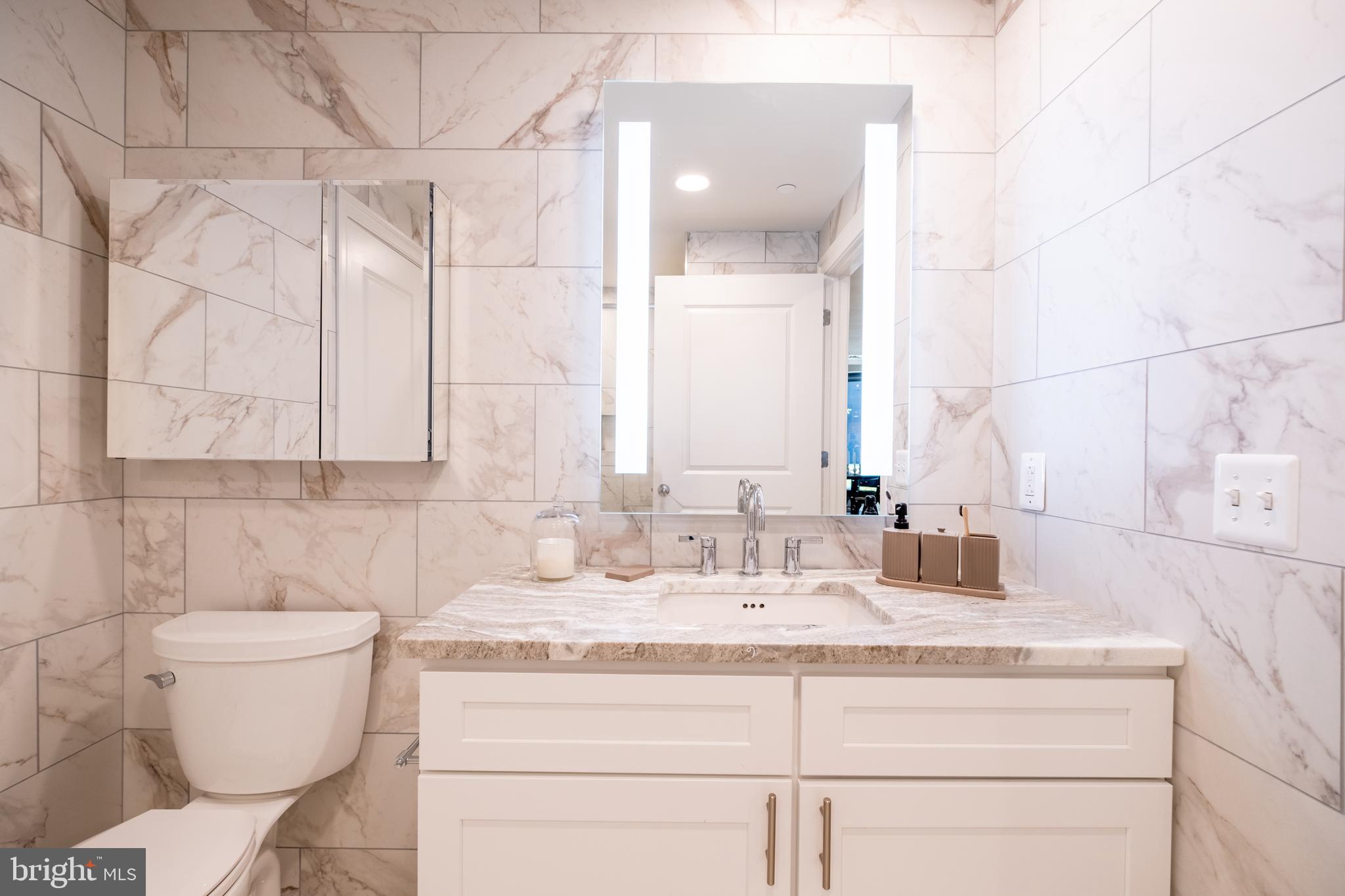 2301-61 John F Kennedy Boulevard, Unit 103 Philadelphia, PA 19103 - Photo 18 of 41 a bathroom with a granite countertop sink a toilet and a mirror