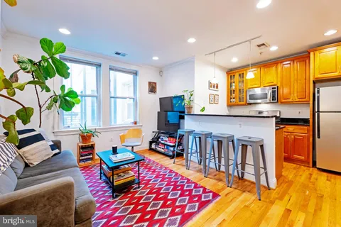 a living room with furniture and a dining table with wooden floor