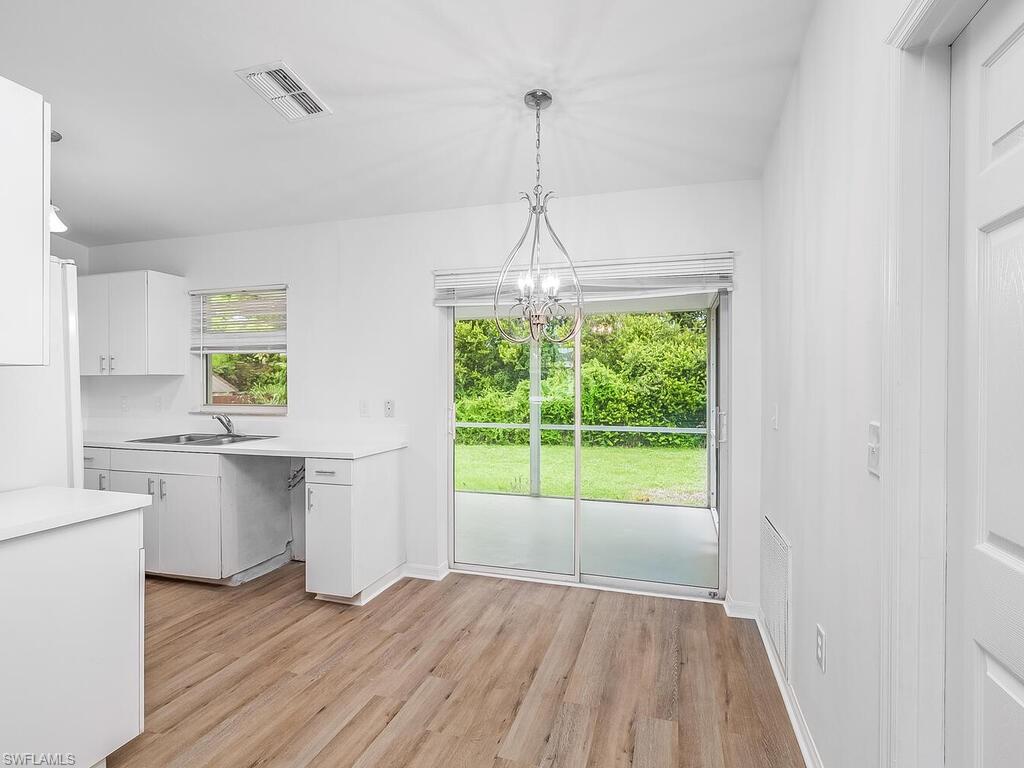 17432 Lee Road Fort Myers, FL 33967 - Photo 5 of 24 a kitchen with kitchen island white cabinets and wooden floor