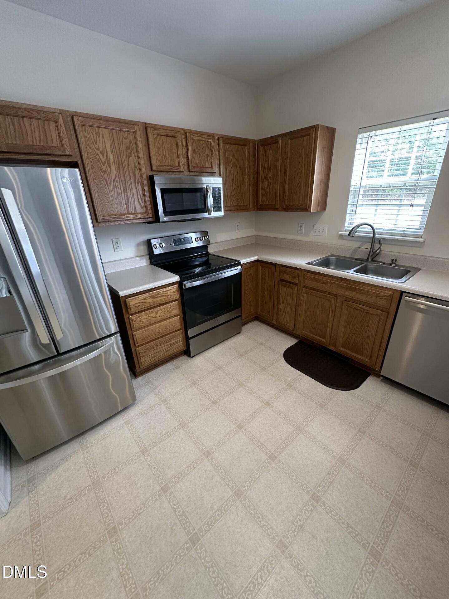 2241 Spruce Shadows Lane Raleigh, NC 27614 - Photo 6 of 18 a kitchen with stainless steel appliances granite countertop a refrigerator a stove a sink a microwave and wooden cabinets