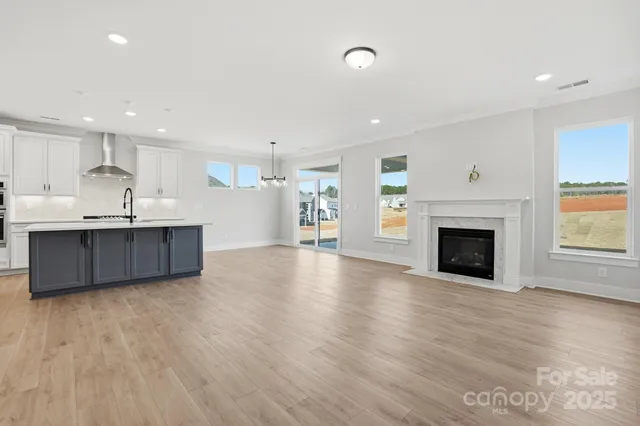 a living room with stainless steel appliances kitchen island wooden floors and fireplace