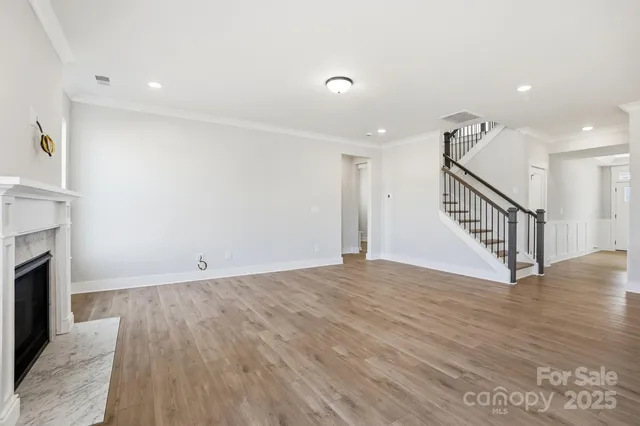 a view of an empty room with wooden floor and a fireplace