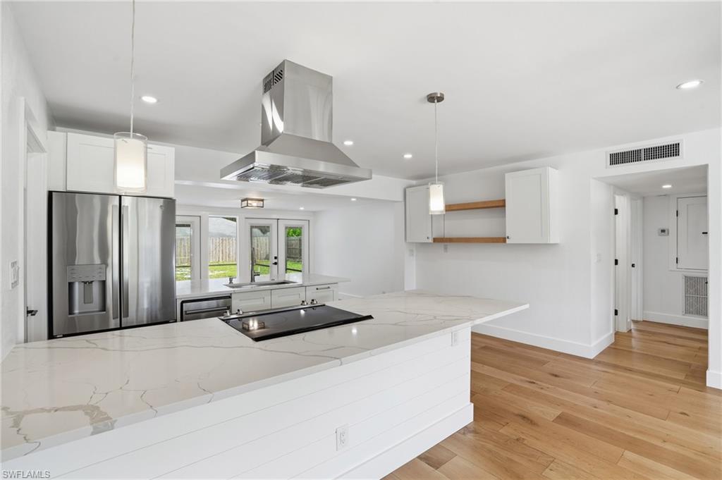 1205 Hilltop Drive Naples, FL 34103 - Photo 4 of 15 a kitchen with stainless steel appliances kitchen island granite countertop a refrigerator a stove and a wooden floors
