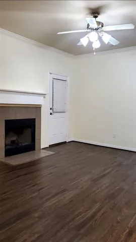 a view of an empty room with wooden floor fireplace and a window