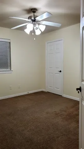 an empty room with a chandelier fan and windows
