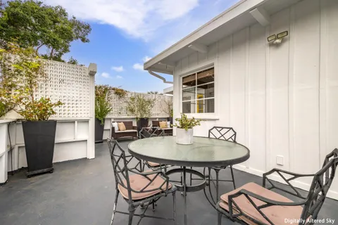 a patio with table and chairs and potted plants
