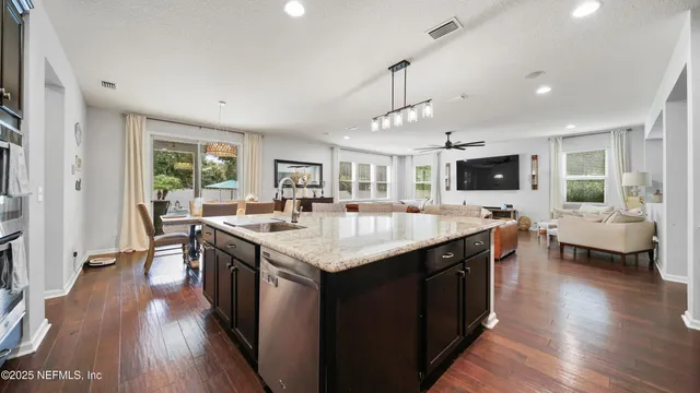 a living room with furniture kitchen view and a wooden floor