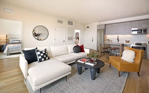 a living room with furniture a rug kitchen view and a window