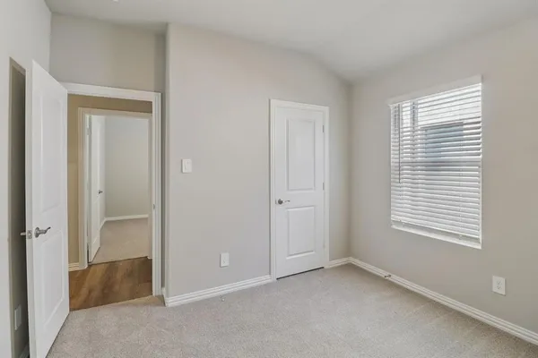 a view of an empty room with closet and a window