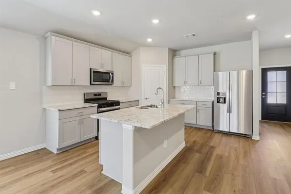 a kitchen with stainless steel appliances a stove a sink a refrigerator and white cabinets