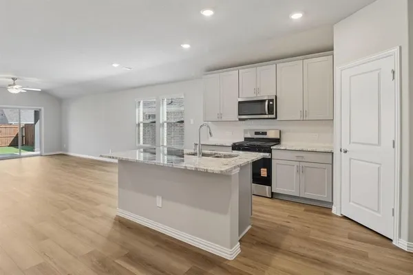 a kitchen with stainless steel appliances granite countertop a stove top oven a sink and white cabinets