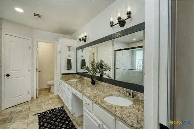 a bathroom with a granite countertop sink a toilet a mirror and shower
