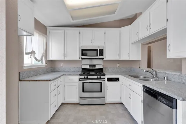 a kitchen with white cabinets appliances and a sink