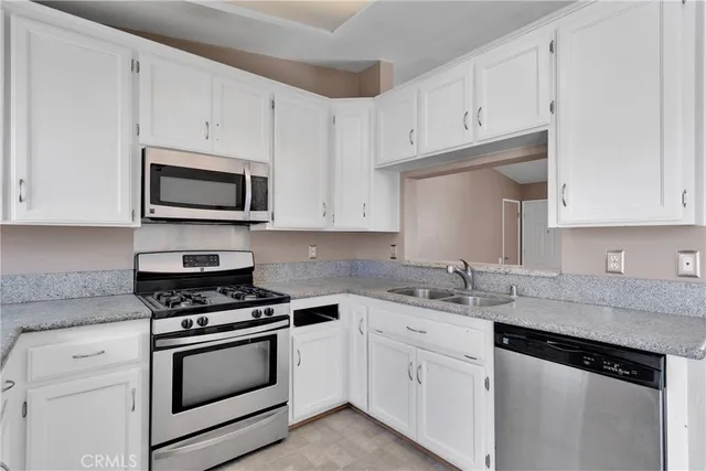 a kitchen with granite countertop white cabinets and stainless steel appliances
