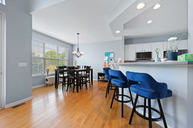 a kitchen with stainless steel appliances granite countertop table chairs and wooden floor