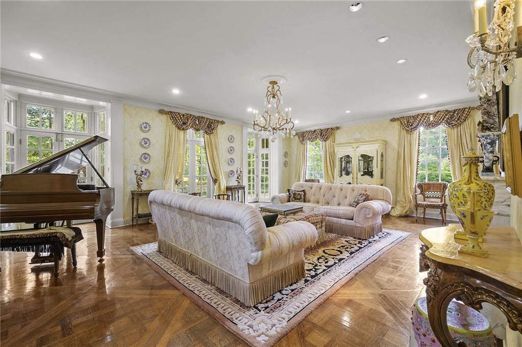 898 Persimmon Road Sewickley, PA 15143 - Photo 11 of 50 Gleaming herringbone parquet floors, crystal chandeliers, and ornate crown molding frame the space, while a marble fireplace serves as a striking focal point.