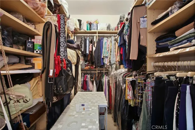 a view of walk in closet with clothes and shoes