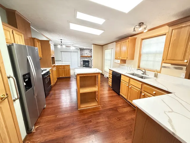 a large kitchen with stainless steel appliances a refrigerator a stove a sink dishwasher and wooden cabinets with wooden floor