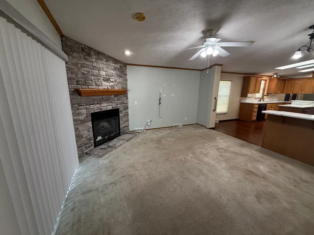 a view of empty room with fireplace and kitchen view