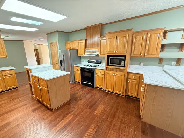 a kitchen with stainless steel appliances granite countertop a stove a sink dishwasher and a refrigerator with wooden floor
