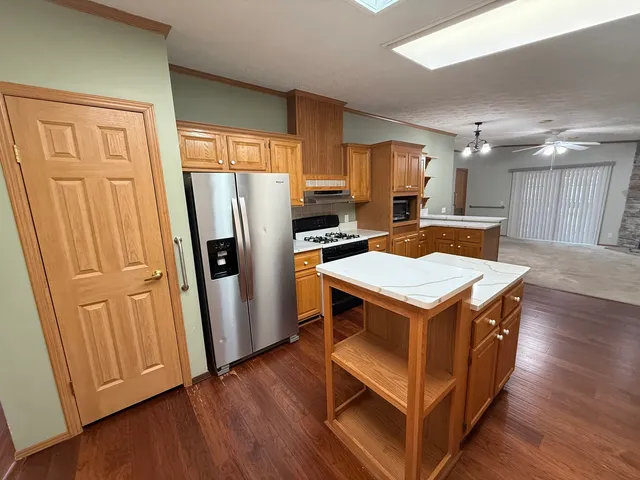 a kitchen with a refrigerator a stove a sink dishwasher and wooden cabinets with wooden floor