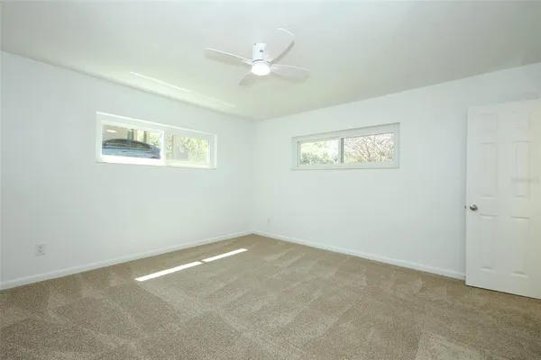 an empty room with a window and ceiling fan