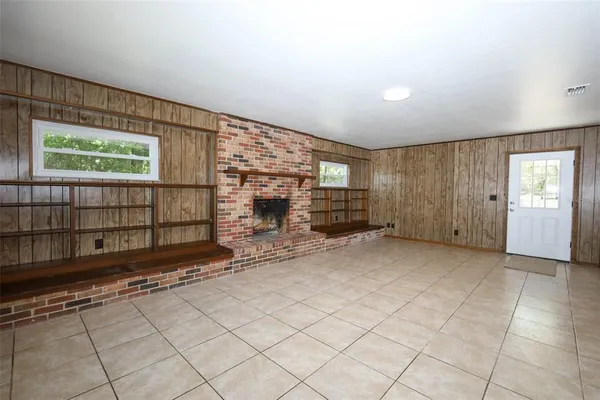 an empty room with windows and fireplace
