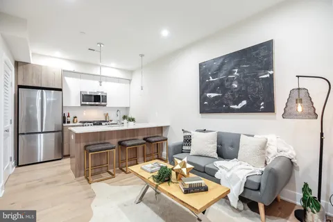 a living room with furniture a refrigerator and kitchen view