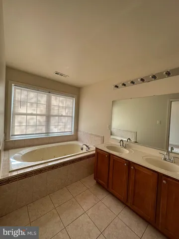 a spacious bathroom with a tub sink and mirror