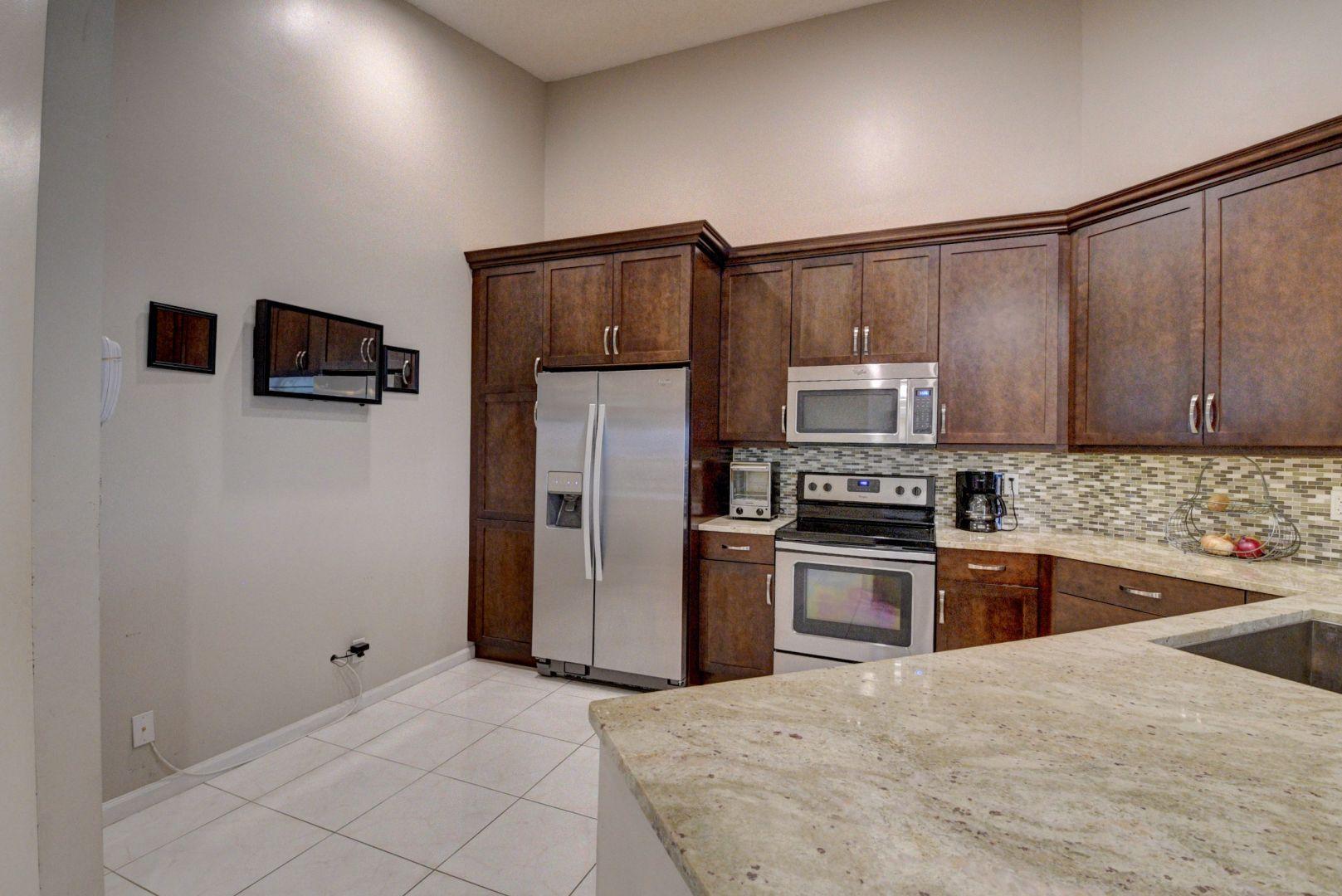 9238 Vineland Court, Unit G Boca Raton, FL 33496 - Photo 13 of 42 a kitchen with granite countertop a refrigerator and a stove top oven