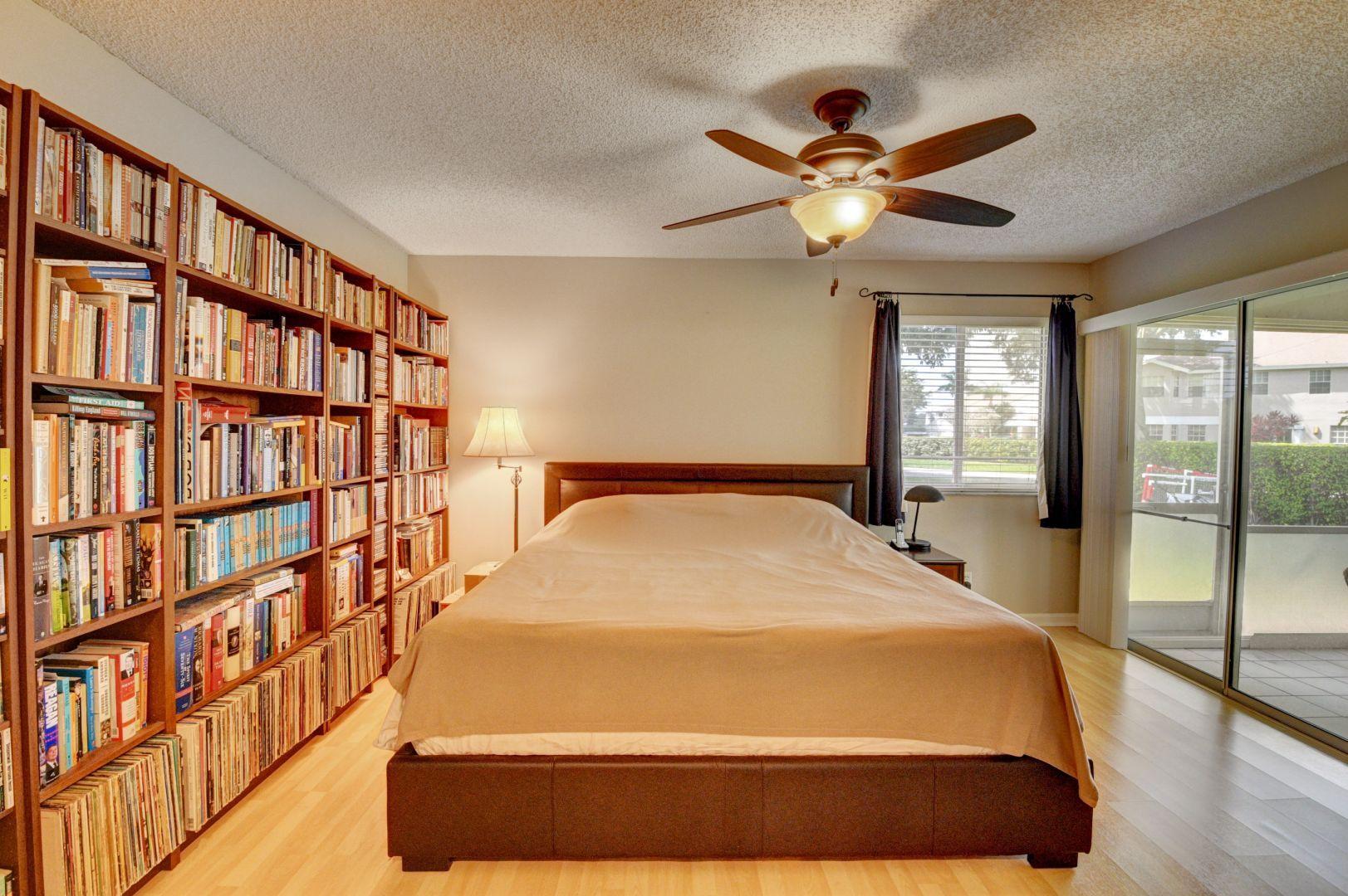 9238 Vineland Court, Unit G Boca Raton, FL 33496 - Photo 17 of 42 a bed sitting in a bedroom next to a book shelf