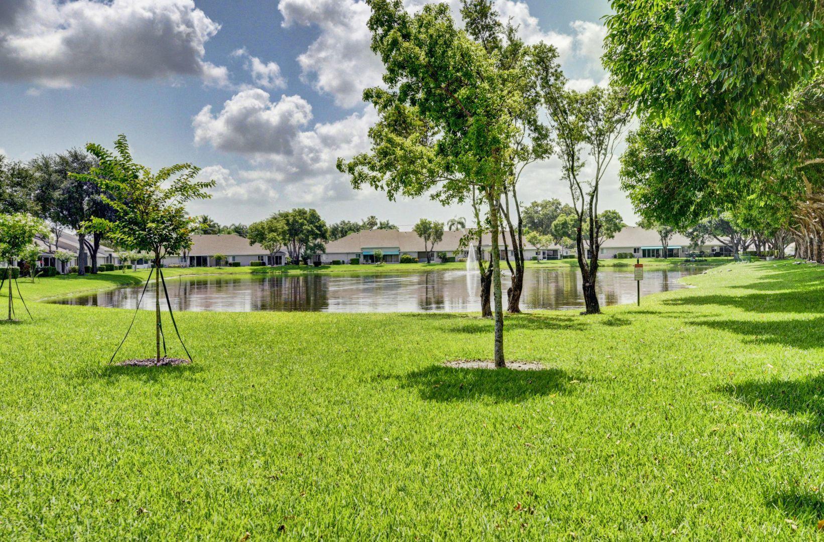 9238 Vineland Court, Unit G Boca Raton, FL 33496 - Photo 26 of 42 a swimming pool with lots of green space and trees in the background
