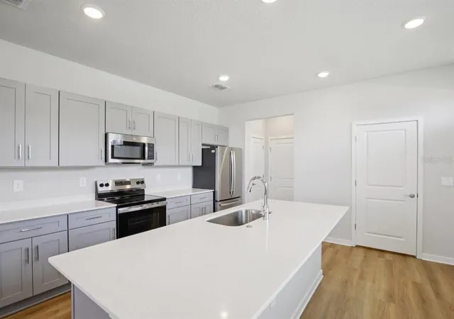 a kitchen with stainless steel appliances a kitchen island hardwood floor sink and stove