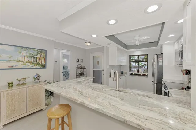 a room with kitchen island a sink and natural light