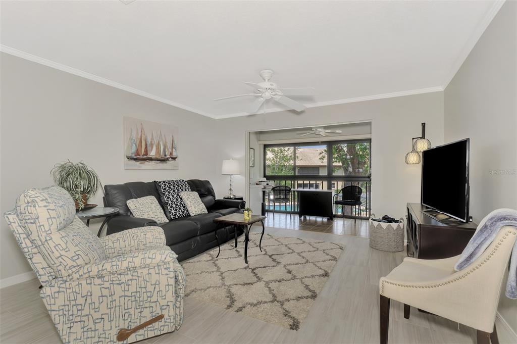 285 Mission Trail West, Unit B Venice, FL 34285 - Photo 25 of 49 a living room with furniture a floor to ceiling window and a flat screen tv