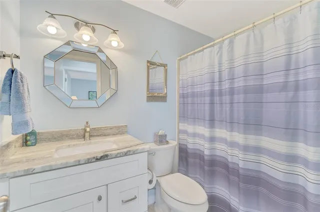 a bathroom with a granite countertop sink a mirror and a toilet