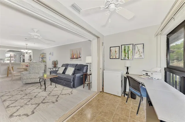 a living room with furniture a chandelier fan and a window