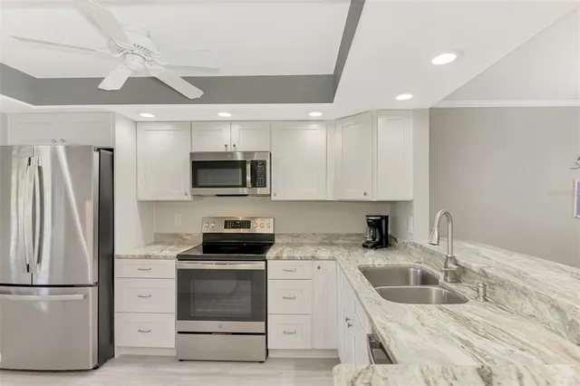 a kitchen with granite countertop a refrigerator stove and sink