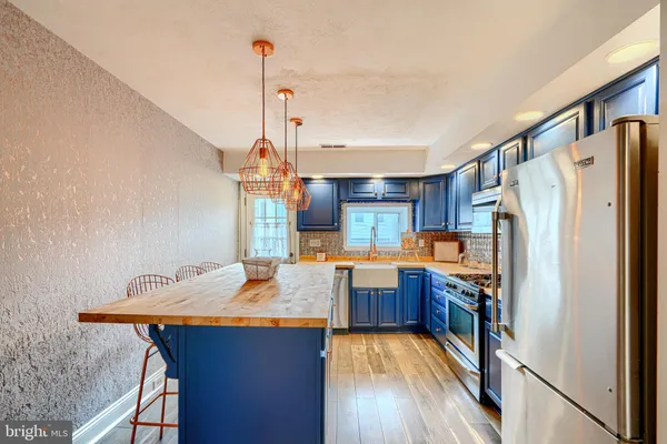 a kitchen with stainless steel appliances granite countertop a refrigerator a sink dishwasher a stove and a countertop with wooden floor