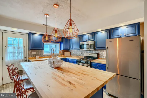 a kitchen with stainless steel appliances kitchen island granite countertop a sink stove and refrigerator