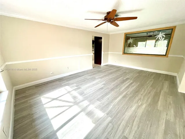 an empty room with wooden floor fan and windows