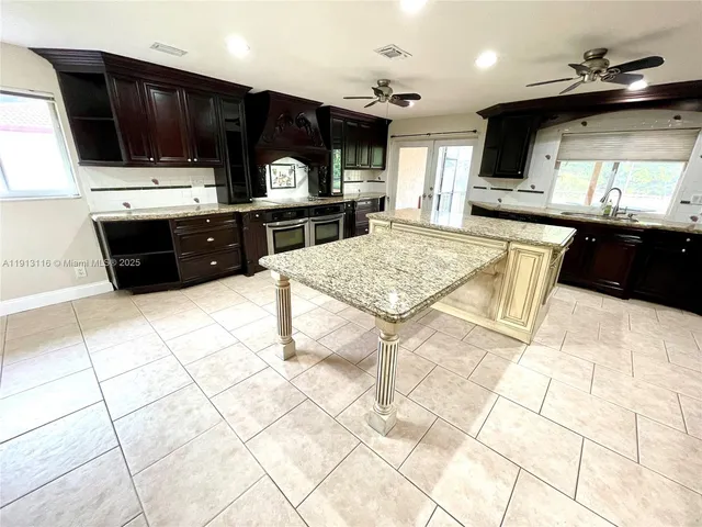 a large kitchen with granite countertop a sink and cabinets