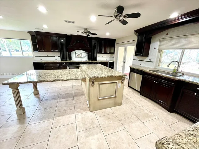 a kitchen with stainless steel appliances kitchen island granite countertop a sink stove and cabinets