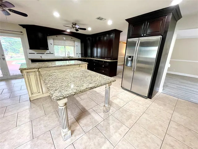 a kitchen with stainless steel appliances kitchen island granite countertop a refrigerator and a stove top oven