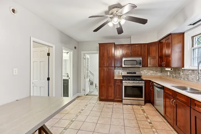 a kitchen with stainless steel appliances granite countertop a refrigerator a sink a stove top oven and a dishwasher with wooden floor