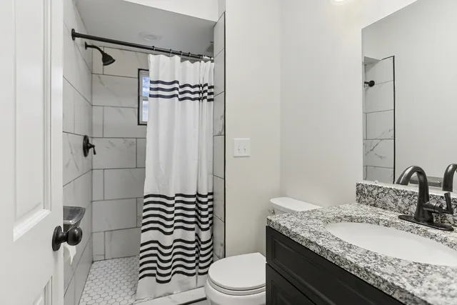 a bathroom with a granite countertop sink toilet mirror and shower