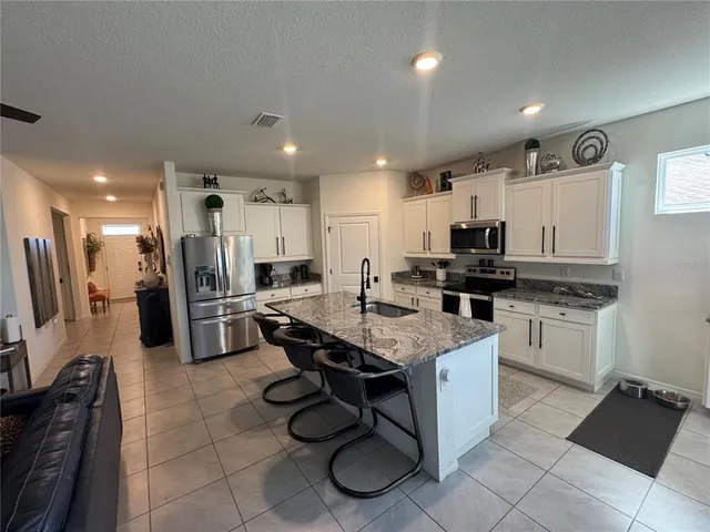 a kitchen with stainless steel appliances kitchen island granite countertop a sink refrigerator and cabinets